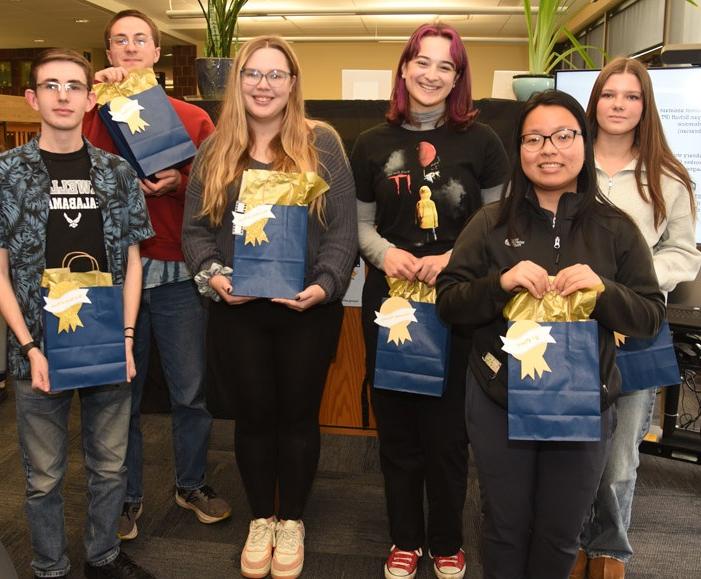 Six people standing together holding prize bags